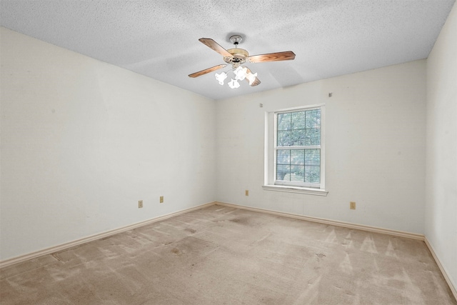 empty room featuring a textured ceiling, light colored carpet, and ceiling fan