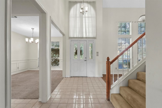 foyer with a chandelier, a textured ceiling, and light colored carpet