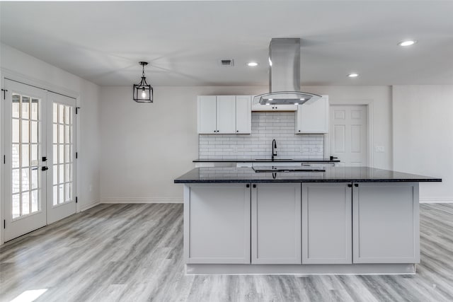 kitchen featuring white cabinets, dark stone countertops, plenty of natural light, and island exhaust hood