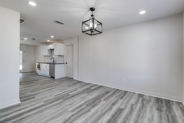 unfurnished living room with light hardwood / wood-style flooring, a notable chandelier, and sink