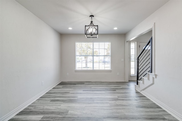 unfurnished dining area with a chandelier and light hardwood / wood-style flooring