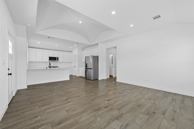 unfurnished living room with vaulted ceiling and light hardwood / wood-style floors