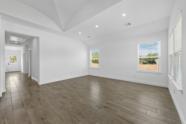 spare room featuring lofted ceiling, a wealth of natural light, and dark hardwood / wood-style floors