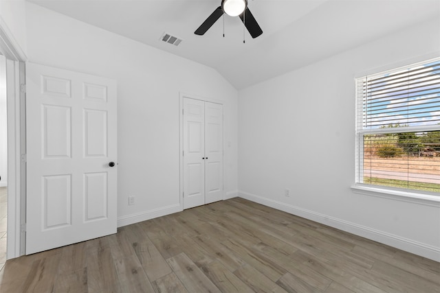 unfurnished bedroom featuring lofted ceiling, a closet, ceiling fan, and wood-type flooring