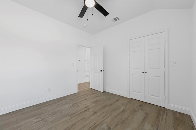 unfurnished bedroom with light wood-type flooring, a closet, ceiling fan, and lofted ceiling