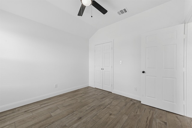 unfurnished bedroom with dark wood-type flooring, a closet, ceiling fan, and vaulted ceiling