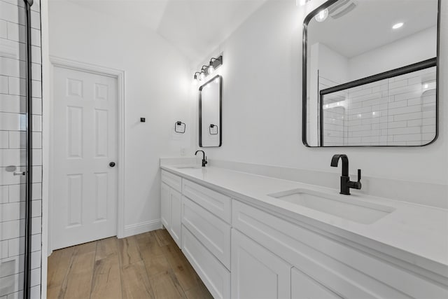 bathroom featuring wood-type flooring, a shower with door, vaulted ceiling, and vanity