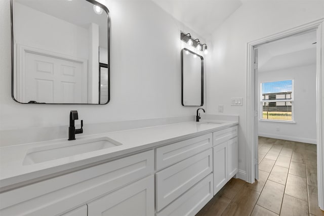 bathroom featuring vanity, vaulted ceiling, and wood-type flooring