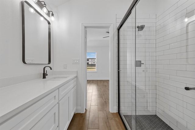 bathroom featuring wood-type flooring, a shower with door, and vanity