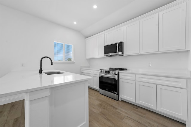 kitchen featuring light hardwood / wood-style flooring, stainless steel appliances, sink, lofted ceiling, and white cabinets