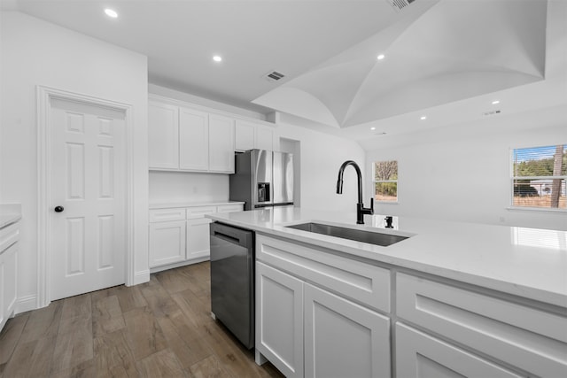 kitchen with light wood-type flooring, stainless steel appliances, white cabinetry, and sink