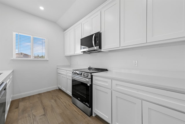 kitchen with lofted ceiling, light wood-type flooring, appliances with stainless steel finishes, and white cabinets