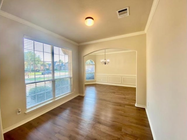 unfurnished room featuring an inviting chandelier, ornamental molding, and dark hardwood / wood-style flooring