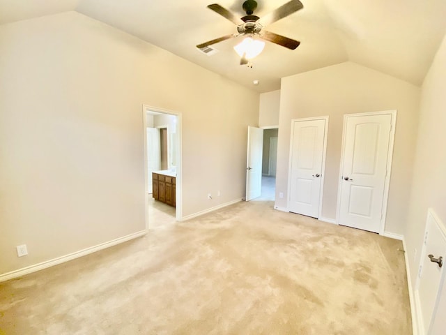 unfurnished bedroom featuring light carpet, ceiling fan, connected bathroom, and vaulted ceiling