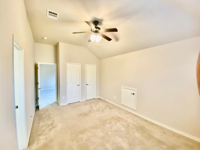 unfurnished bedroom featuring light colored carpet, vaulted ceiling, and ceiling fan