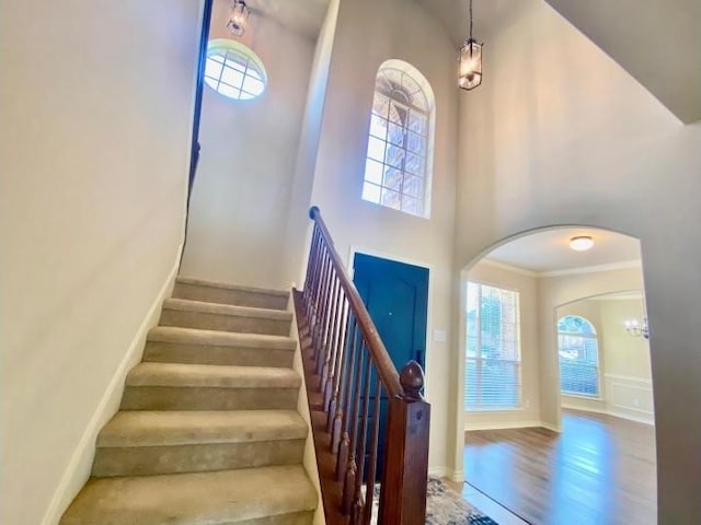 stairs with ornamental molding, a high ceiling, and hardwood / wood-style floors