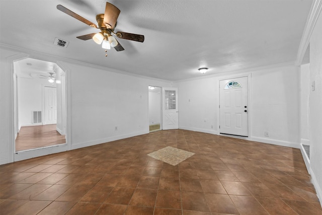 spare room with dark tile patterned floors, crown molding, and ceiling fan