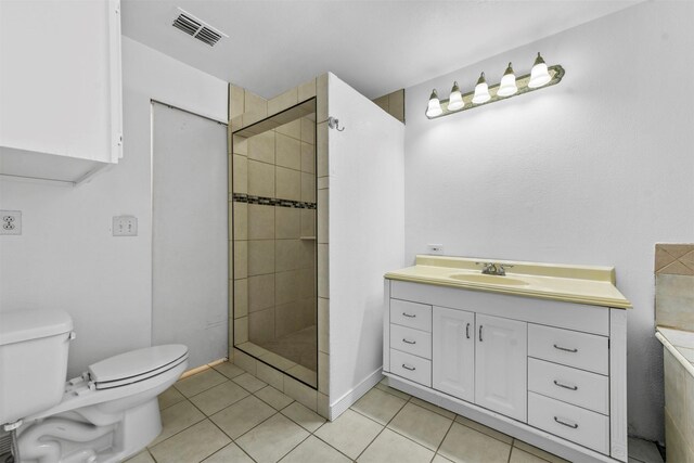 bathroom featuring vanity, toilet, tile patterned flooring, and a tile shower