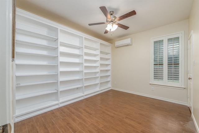 spare room with ceiling fan, plenty of natural light, an AC wall unit, and wood-type flooring