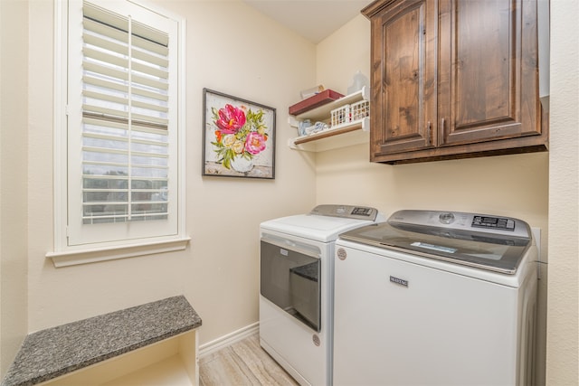 clothes washing area featuring cabinets, light hardwood / wood-style floors, and washer and clothes dryer