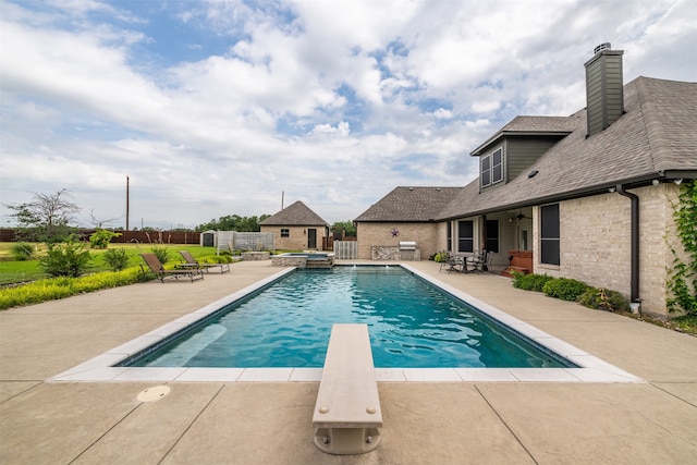 view of swimming pool featuring a diving board and a patio