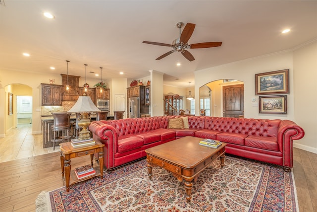 living room featuring ceiling fan, ornamental molding, and light hardwood / wood-style floors