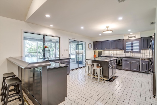 kitchen featuring refrigerator, backsplash, a kitchen island, sink, and a breakfast bar