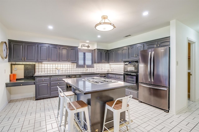 kitchen featuring a center island, stainless steel appliances, a kitchen breakfast bar, and tasteful backsplash