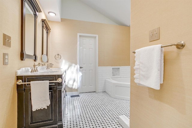 bathroom with lofted ceiling, vanity, tile walls, and a washtub