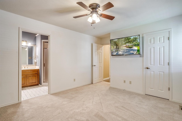 unfurnished bedroom featuring ceiling fan, light colored carpet, connected bathroom, and sink