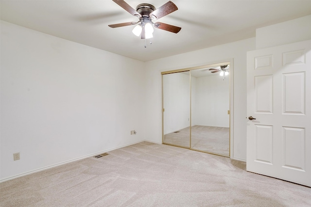 unfurnished bedroom with a closet, ceiling fan, and light colored carpet