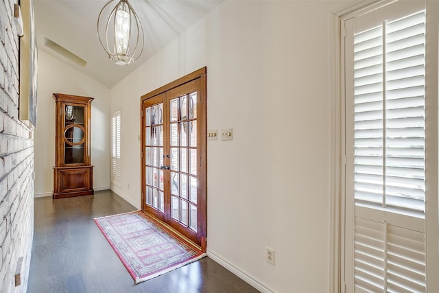 doorway to outside featuring lofted ceiling, plenty of natural light, dark hardwood / wood-style floors, and a notable chandelier