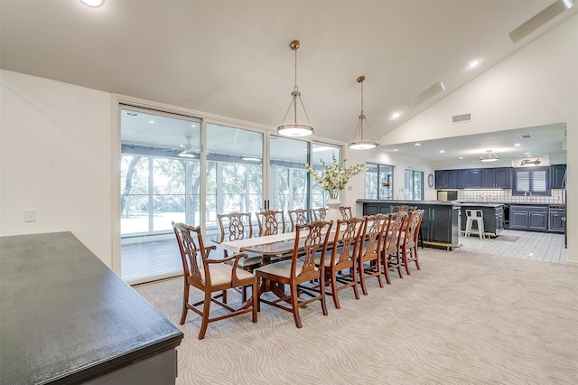 dining area with plenty of natural light, sink, high vaulted ceiling, and light colored carpet