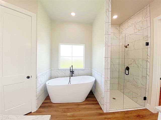 bathroom with tile walls, independent shower and bath, and wood-type flooring