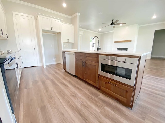 kitchen with a center island with sink, stainless steel appliances, white cabinetry, ceiling fan, and light wood-type flooring