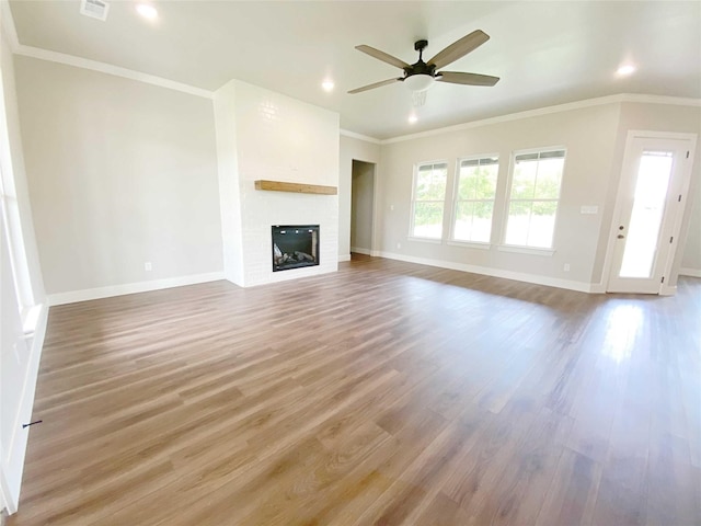 unfurnished living room with ceiling fan, ornamental molding, hardwood / wood-style flooring, and a fireplace