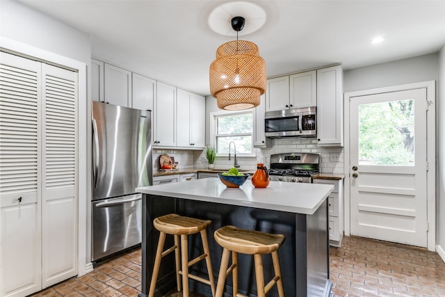 kitchen featuring pendant lighting, white cabinets, stainless steel appliances, and a wealth of natural light