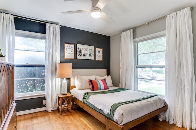 bedroom with multiple windows, ceiling fan, and hardwood / wood-style floors