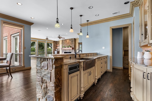 kitchen featuring hanging light fixtures, light stone counters, dark hardwood / wood-style floors, a stone fireplace, and ceiling fan