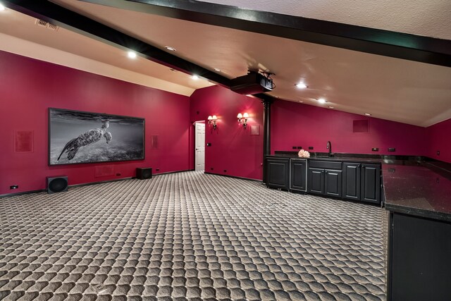 cinema room featuring lofted ceiling with beams, sink, and carpet flooring