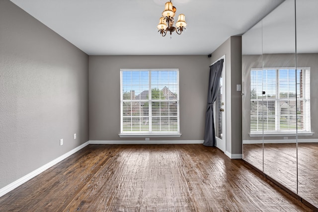 empty room with a chandelier and dark hardwood / wood-style floors