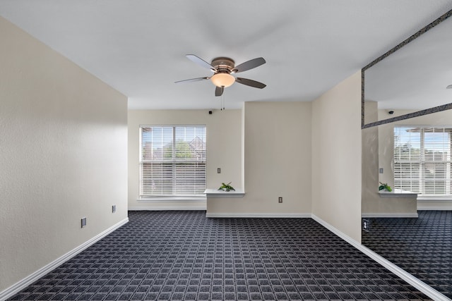 unfurnished room with dark colored carpet and ceiling fan