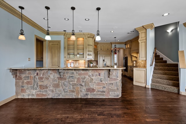 kitchen featuring paneled refrigerator, light stone countertops, backsplash, hanging light fixtures, and hardwood / wood-style flooring