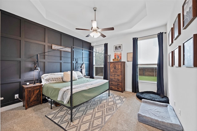 bedroom featuring light colored carpet, ceiling fan, and a raised ceiling