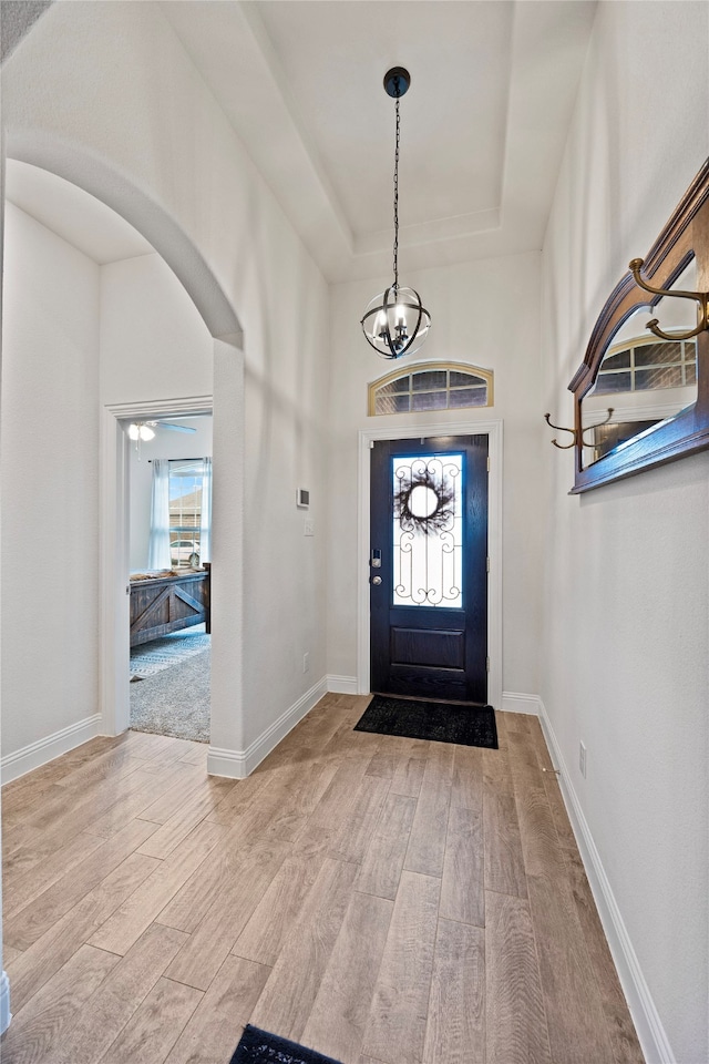 entrance foyer with a tray ceiling, ceiling fan, and light hardwood / wood-style floors