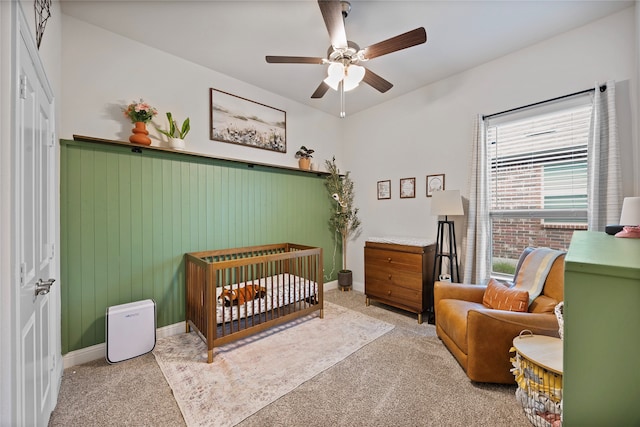 bedroom with light carpet, a nursery area, and ceiling fan