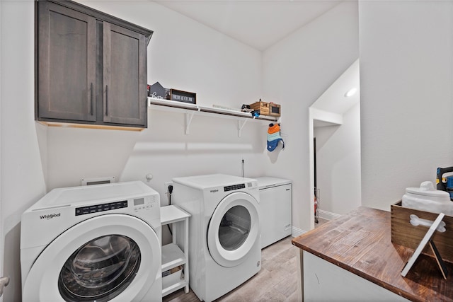 laundry area featuring cabinets, light hardwood / wood-style floors, and independent washer and dryer