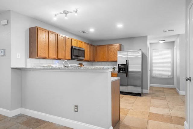 kitchen with light stone counters, stainless steel appliances, and decorative backsplash