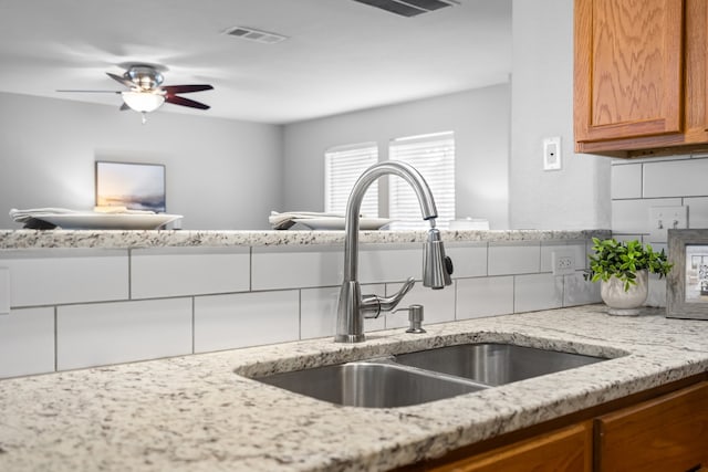 kitchen featuring light stone countertops, sink, ceiling fan, and decorative backsplash