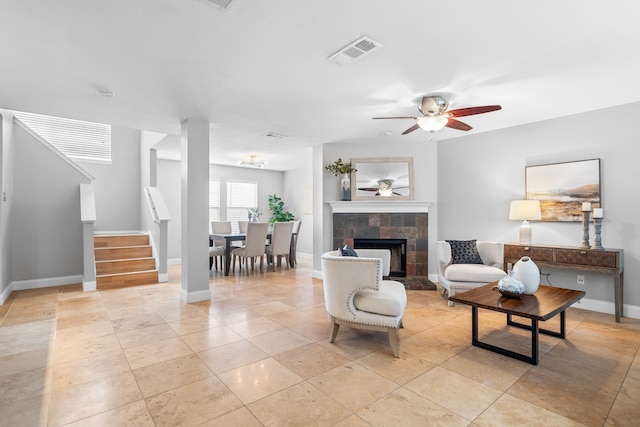 tiled living room with ceiling fan and a tile fireplace